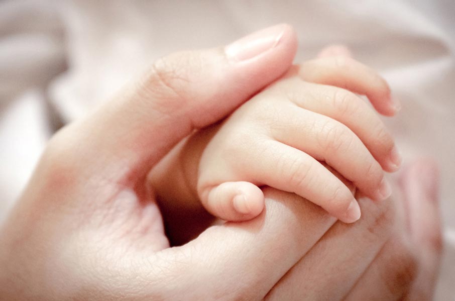 Mothers hand holding baby's hand macro shot